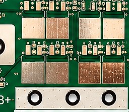 Double-sided aluminum PCB close-up: copper thermal pads and plated through-holes on the aluminum core